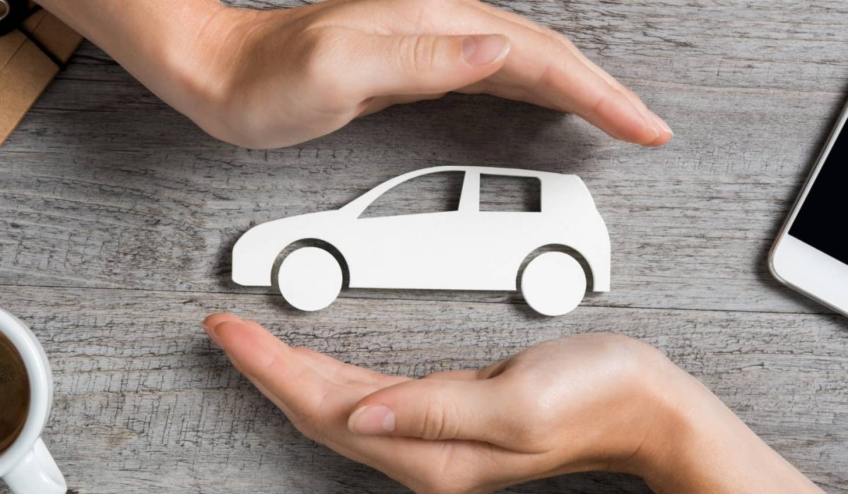An image of a set of hands protecting a small car model